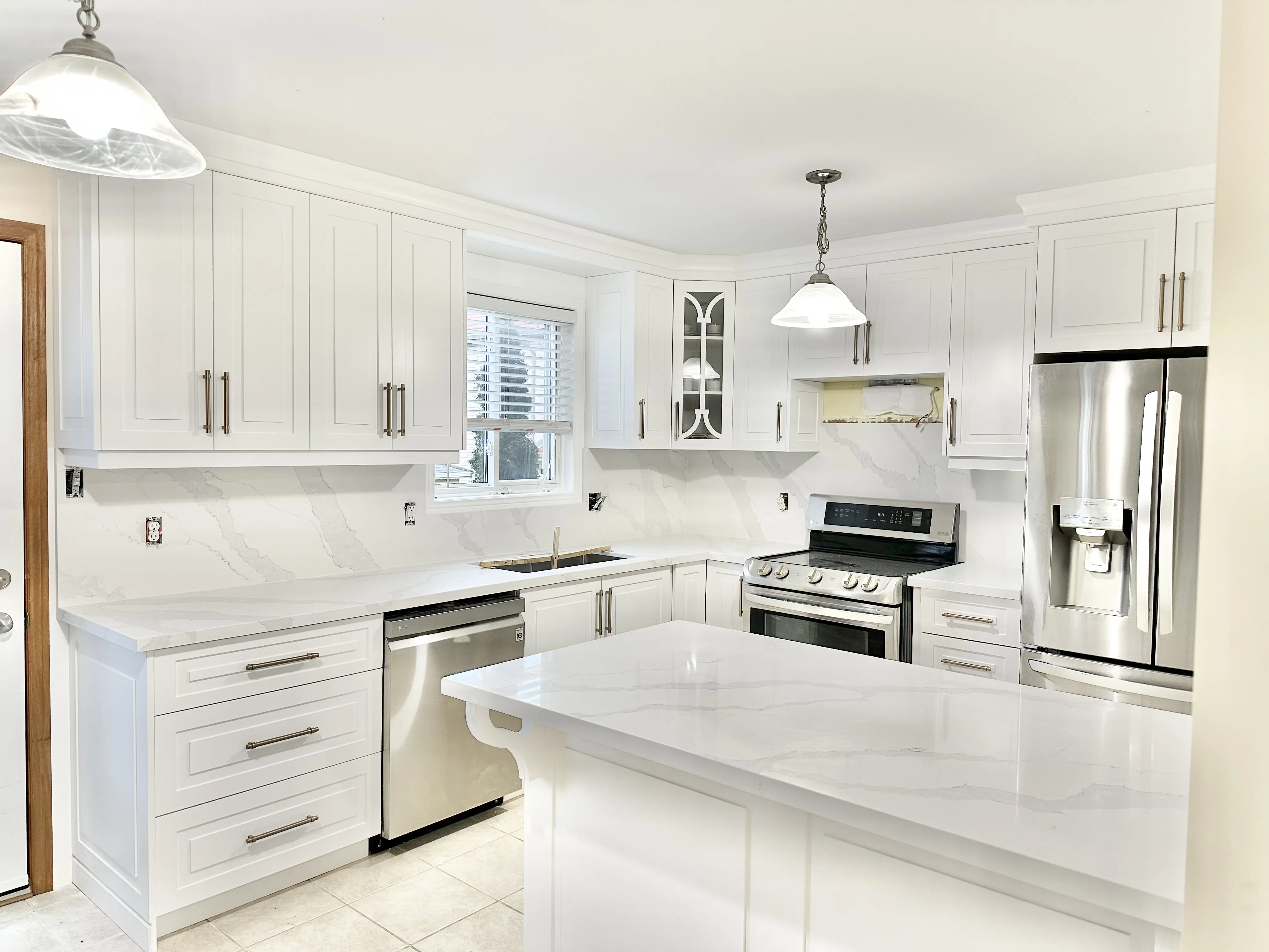 Bright kitchen with white stone countertops, a broad island, and pendant lighting