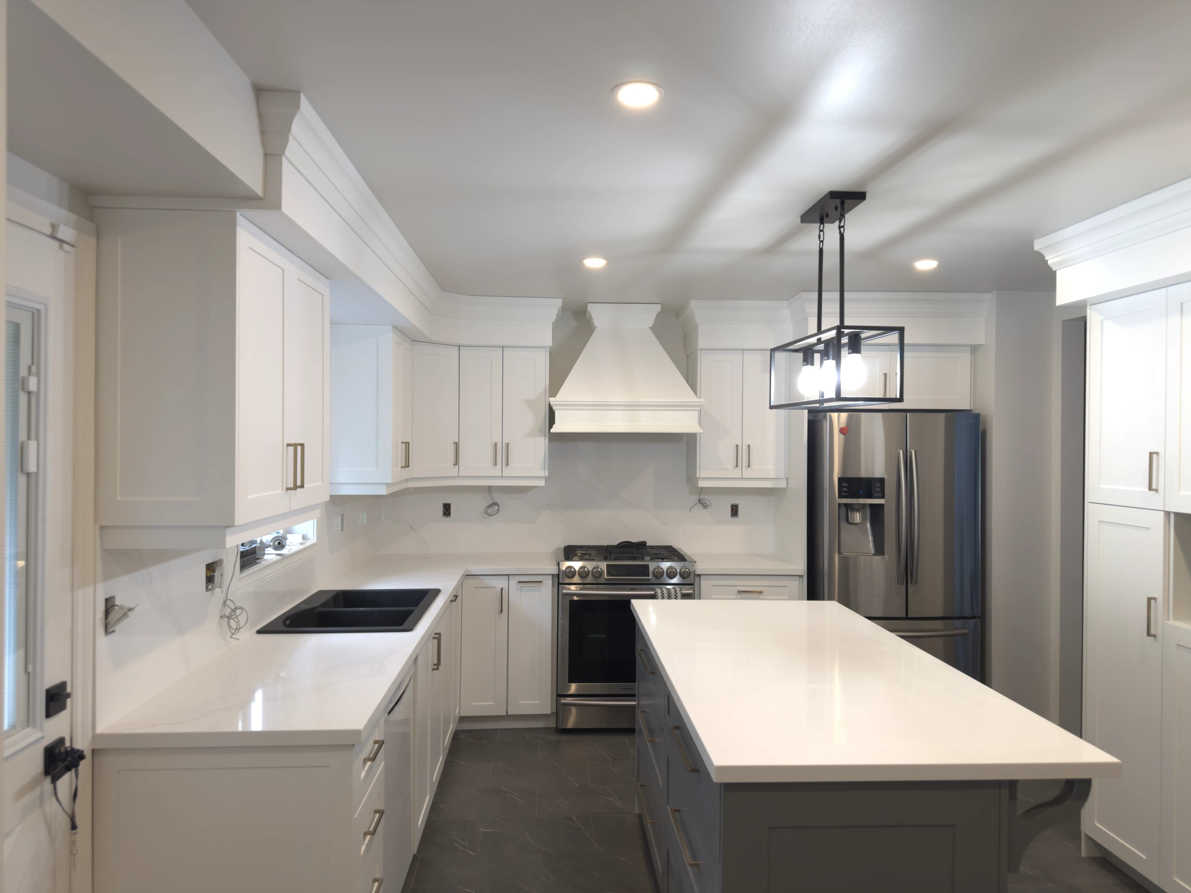 Installed white stone island and countertops in a kitchen with a black sink